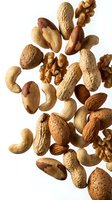 Mixed nuts falling on white background including almonds, walnuts, cashews, brazil nuts and peanuts for healthy snacking and cooking recipes.