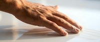 Male hand with warm skin tone resting on white surface in soft natural light, conveying calm, relaxation, and mindfulness for wellness and meditation concepts.