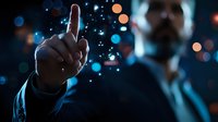 Businessman in suit pointing upward with glowing digital particles and bokeh lights creating futuristic atmosphere against dark background.