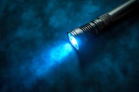 Powerful LED flashlight beam cutting through atmospheric smoke with bright blue light and dramatic dark background for emergency and security concepts.