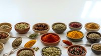 Colorful spices and herbs in wooden bowls and spoons arranged on white background. Cooking ingredients for culinary recipes and seasoning food preparation.