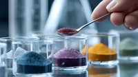 Laboratory research with colorful powder samples in glass containers. Hand with metal spoon adding substance for scientific experiment or chemical analysis.