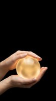 Hands protecting glowing golden sphere on black background symbolizing care, protection, energy and spiritual power for business concepts.