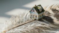 Small wooden house model placed on soft feather surface creating dreamy ethereal atmosphere for real estate mortgage insurance concepts.