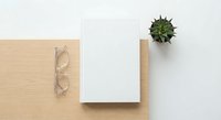 Minimalist workspace with blank notebook, eyeglasses and small succulent plant on wooden desk surface for creative projects and office planning.
