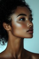 Young African American woman with glowing skin and natural curly hair in profile view against soft blue background for beauty and skincare concepts.