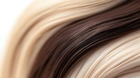 Flowing blonde and brown hair strands creating smooth waves with natural highlights and lowlights for beauty and haircare concepts.