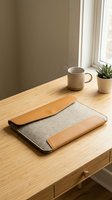 Felt and leather laptop sleeve on a wooden desk with a ceramic mug and succulent plant, cozy minimal workspace setup for productivity.