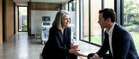 Professional businesswoman and businessman having strategic meeting in modern corporate office with large windows and contemporary interior design.