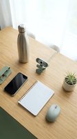 Modern home office workspace with webcam, notebook, smartphone and water bottle on wooden desk for remote work and video conferencing setup.