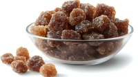 Brown sugar rock candy crystals in glass bowl, crystallized natural sweetener chunks with rough texture and translucent amber color on white background.