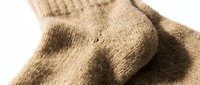 Soft beige wool socks close-up on white background, showing warm knitted texture, cozy winter footwear for cold weather comfort and everyday wear.