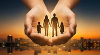 Protective hands forming heart shape around family silhouettes at sunset over city skyline. Insurance, care, security and love concept for family protection.