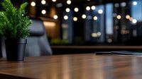 Wooden table surface with potted plant and blurred bokeh lights in dark restaurant interior, creating cozy atmospheric dining ambiance.