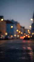 Defocused urban street at dusk with glowing street lights and colorful buildings creating bokeh effect, suitable for backgrounds and atmospheric design projects.