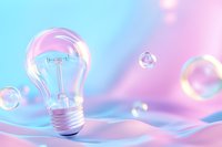Light bulb on soft pink and blue pastel background with floating soap bubbles creates dreamy atmosphere for creative innovation concepts.