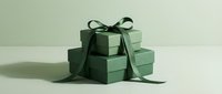 Stack of elegant sage green gift boxes with dark green ribbon bow on neutral background for holiday celebrations and special occasions.