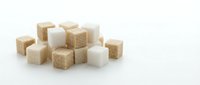 Assorted brown and white sugar cubes arranged in a pile on white background, isolated for culinary, baking, and beverage design projects.