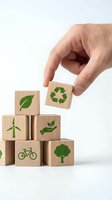 Hand placing wooden cube with recycling symbol on stack of eco-friendly blocks featuring green environmental icons for sustainable business concepts.