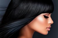 Side profile of young Asian woman with long straight black hair, dramatic winged eyeliner, and glossy pink lips against dark background. For beauty and cosmetics.