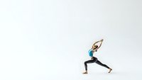 Young athletic woman practicing yoga warrior pose on white background isolated for fitness and wellness design projects.