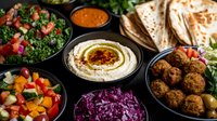 Middle Eastern mezze platter with creamy hummus, falafel, fresh tabbouleh, colorful vegetable salads, purple cabbage, pita bread and dipping sauce served on dark background.