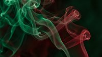 Colorful smoke swirls in green and red hues creating abstract flowing patterns against dark background for creative design projects.