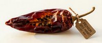 Dried red chili pepper with vintage kraft label tag attached to stem, isolated on white background for culinary, food packaging, recipe, and cooking design projects.