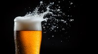 Fresh cold beer with splashing foam and droplets on black background, condensation on glass, golden lager with white frothy head creating dynamic motion.