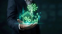 Businessman holding glowing green house icon with percentage symbol, tree and growth chart representing sustainable real estate investment and eco-friendly mortgage rates.