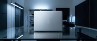 Laptop computer on reflective surface with modern office environment, sleek workspace setup for business and technology concepts.