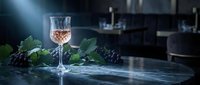 Elegant crystal wine glass filled with rosé wine on marble counter with fresh grape clusters and vine leaves in luxurious kitchen setting for fine dining.