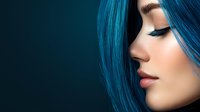 Young Asian woman with vibrant blue hair and dramatic eye makeup in profile view against dark background, showcasing modern beauty and creative hair coloring trends.