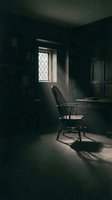 Moody study room with wooden chair positioned at desk near latticed window casting dramatic light through dusty air, surrounded by bookshelves in dark atmospheric setting for creative writing and solitude concepts.
