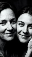 Intimate black and white portrait of smiling senior mother and adult daughter embracing, showing generational bond and family love in monochrome photography.
