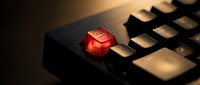 Red emergency stop button on black computer keyboard with dramatic lighting for crisis management and system shutdown concepts.