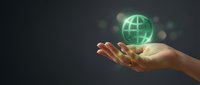 Glowing green globe floating above open palm against dark background representing global connectivity, environmental protection and sustainable future.