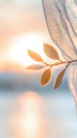 Delicate golden leaves on fabric branch against soft sunset bokeh background creating peaceful natural atmosphere for wellness and mindfulness concepts.
