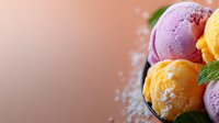 Colorful ice cream scoops with mint garnish in black bowl against blurred background, sprinkled with powdered sugar, showcasing vibrant yellow and purple flavors.