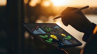 Business professional analyzing financial data charts and graphs on tablet device with stylus pen during golden hour sunset for investment planning.