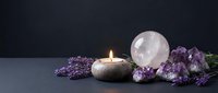 Glowing candle, rose quartz sphere, amethyst crystals and lavender on dark background, creating a serene spiritual wellness atmosphere.