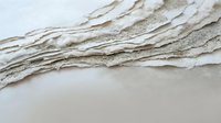 Gentle ocean waves washing onto pristine sandy beach shore with soft foam and bubbles creating peaceful coastal scenery for relaxation and vacation themes.