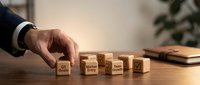 Businessman hand arranging wooden blocks with business strategy concepts on office desk for corporate planning and development.