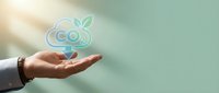 Businessman hand holding CO2 carbon dioxide emission icon with green leaves symbolizing environmental responsibility and sustainable business practices.