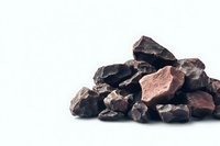 Pile of dark chocolate chunks and pieces isolated on white background, raw cacao nibs closeup. Culinary and confectionery concept for food design.
