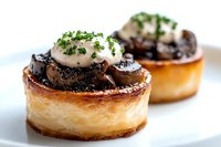 Gourmet mushroom vol au vent pastries topped with creamy sauce and fresh herbs on white plate. Elegant French appetizer with sauteed mushrooms and parsley garnish.