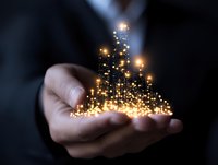 Glowing golden city skyline silhouette floating above open palm, magical light particles creating urban landscape shape with sparkles and bokeh effect in dark background.