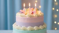 Birthday cake with lit candles and colorful decorations on pastel background with bokeh lights for celebration party events.