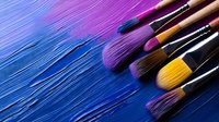 Professional makeup brushes arranged diagonally on vibrant blue and purple background with dynamic light streaks creating artistic cosmetic composition for beauty industry.