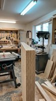 Professional woodworking workshop with laminated plywood board showing detailed edge grain layers and craftsmanship tools in background for furniture making.